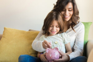 Mutter und Tochter stecken Geld in ein Sparschwein